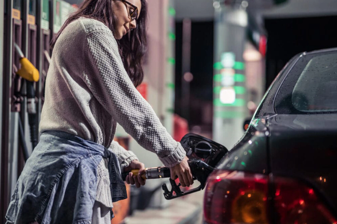 woman filling up her gas tank at night