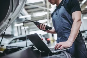 auto mechanic with diagnostic tool and laptop